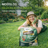 Eine lächelnde Frau in Gartenarbeiterkleidung lehnt sich an einen TerraUno Rasendünger mit Eisen - Mooslos Glücklich - Angebot Beutel in einem üppigen Garten. Der Text hebt ihn als ideal für Moosverdrängung und das Erreichen eines tiefgrünen Rasens hervor.