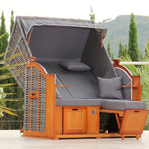 Der DERKORB Der Klassiker 2-Sitzer ist ein moderner Outdoor-Polyrattan-Strandkorb mit grauen Kissen, Kiefernholz-Gestell, Baldachin, integrierten Fußstützen, Beistelltischen, Armlehnen und Wurfkissen - perfekt für Ihre Terrasse.