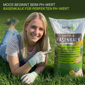 Eine lächelnde blonde Frau kniet im Gras und hält eine Tüte „TerraUno Rasendünger mit Eisen – Mooslos Glücklich“ in der Hand. Der Text darüber hebt die Vorteile dieses Rasendüngers mit Eisen für einen perfekten pH-Wert und eine wirksame Moosbekämpfung hervor. Der Sack wirbt mit Vorteilen wie verbesserter Bodenqualität, zusätzlichem Magnesium und einem üppig grünen Rasen – ideal für alle, die mehr als nur gewöhnlichen Rasendünger mit Eisen suchen.