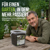 Gartenbesitzer mit TerraUno Soldatenfliegenlarven-Eimer am Gartentisch – Futter für heimische Wildvögel