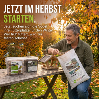 Gartenbesitzer füllt im Herbst das Futterhaus mit TerraUno Wildvogelfutter, Meisenknödel und Soldatenfliegenlarven auf dem Gartentisch